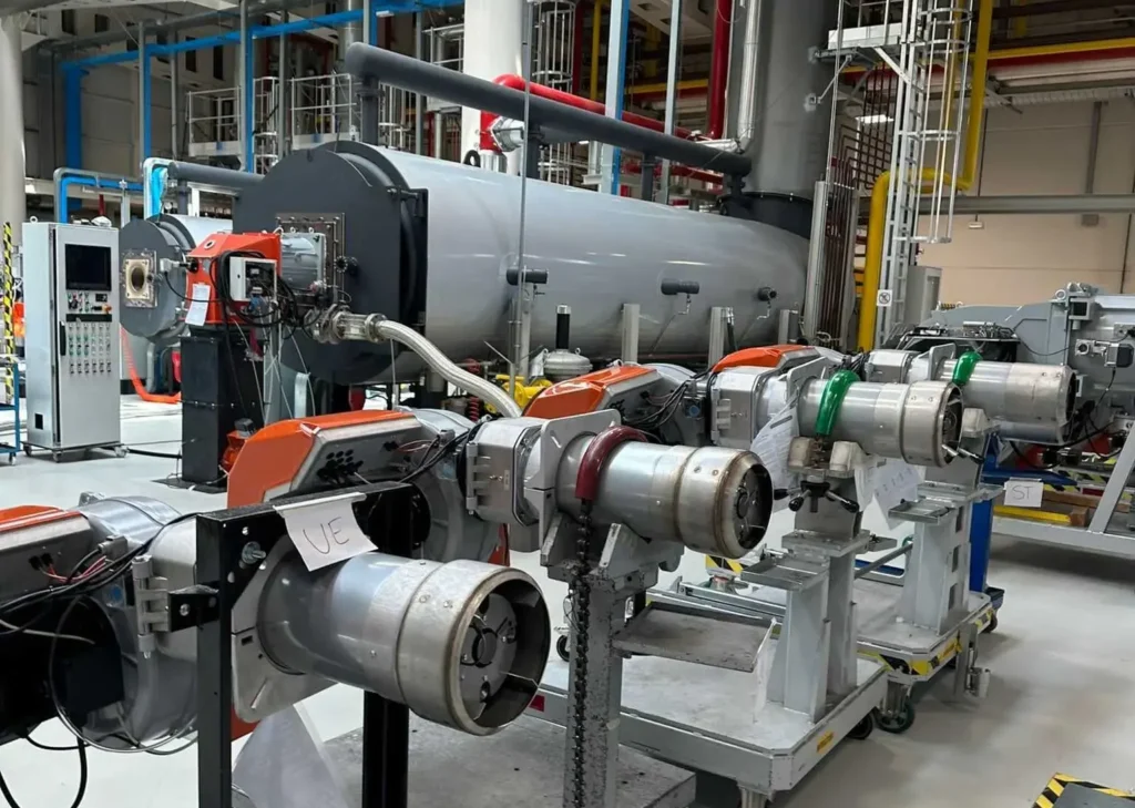 A row of industrial burner units mounted on stands in a modern training facility, demonstrating advanced heating technology and energy solutions.